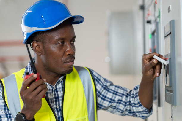 男电工或男电子技师负责控制室电气系统的维修。非裔美国电工男工程师在控制室检查电气系统图片下载