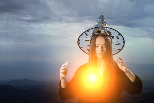 女巫用山火，万圣节又施魔法，女孩戴着帽子用火球变戏法，所有圣徒都以除夕、节日为背景图片下载