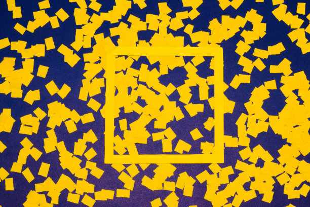 黄色画框作为拷贝空间在深蓝色的背景上，整个背景覆盖着黄色的碎纸，创意艺术设计，拷贝空间，抽象设计图片下载