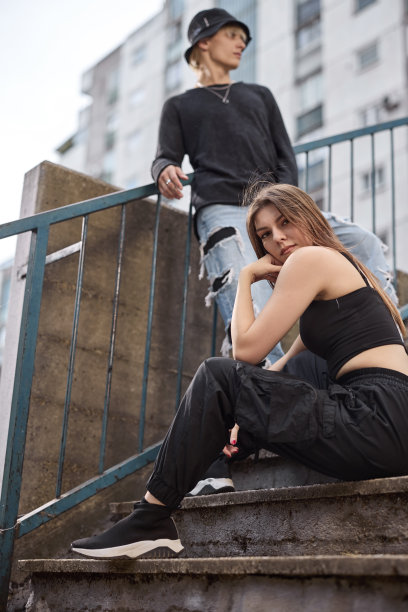 一对十几岁的情侣在建筑物环绕的楼梯上拍照。图片下载