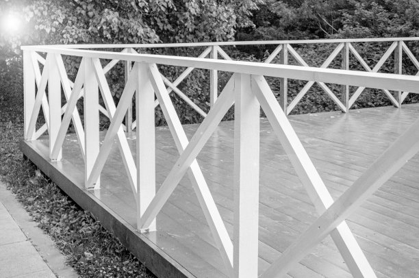 室外夏季露台与木制地板和栏杆的形式，在树木的背景下，特写，黑白镜头，单色图片下载