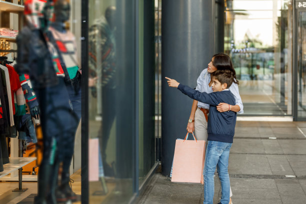 年轻的妈妈带着可爱的儿子逛商场，逛橱窗。图片下载
