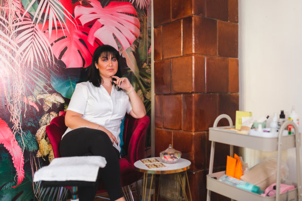 年轻的美容师坐在她的专业沙龙在足疗站的肖像图片下载