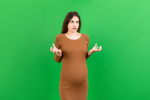 年轻美丽的少女怀孕期待婴儿在孤立的有色背景，侵略性的表情和手臂举起。挫折的概念图片下载