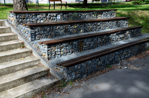 在公园的看台上，有一个混凝土楼梯，由石笼筐组成，里面放着灰色的石头。长凳的座位区是用木板做成的台阶。图片下载