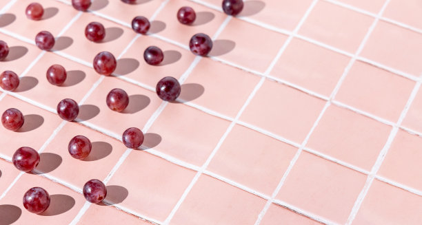 红色的葡萄沿着粉红色的格子瓦片一字排开图片下载