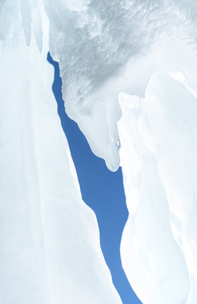 俄罗斯西伯利亚贝加尔湖奥戈伊岛岩石上的冰和冰柱。白色的冰和蓝色的天空背景。图片下载