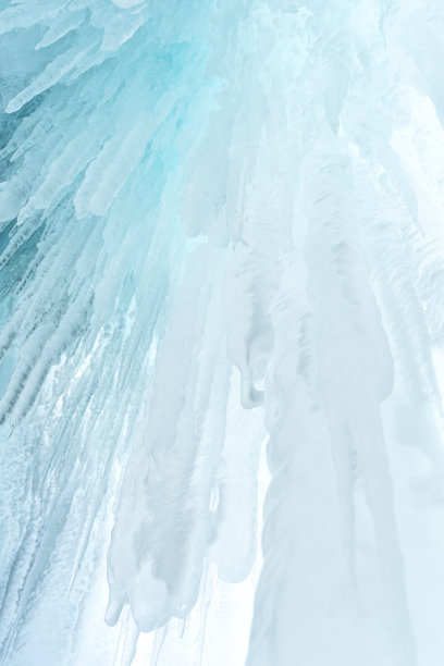 俄罗斯西伯利亚贝加尔湖奥戈伊岛岩石上的冰和冰柱。白色的冰和蓝色的天空背景。图片下载