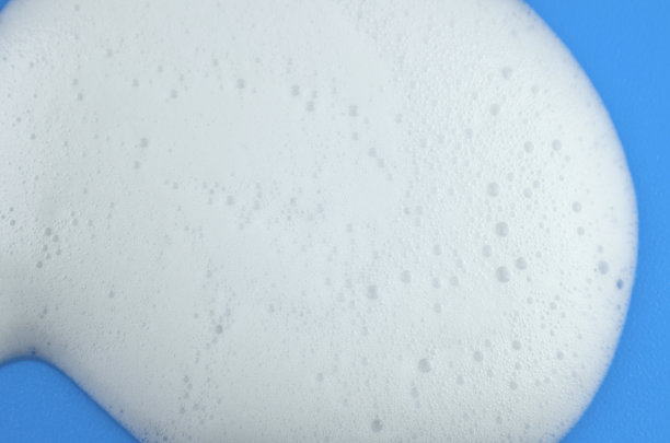 蓝色背景的白色洗发水泡沫或洗涤泡沫的微距照片图片下载