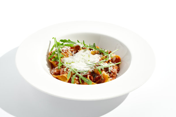 意大利意大利面配肉酱和帕尔马干酪，白色背景。意式细面条配肉酱和奶油espuma配芝麻菜。意大利面配蕃茄酱碎牛肉。图片下载