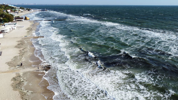 阳光明媚的日子，人们在海滩上散步和放松。无人机观察飞行图片下载