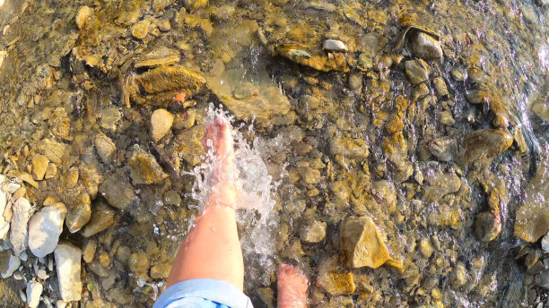 姑娘光脚水花洒在河面浅浅的石头上特写，阳光明媚的夏天图片下载
