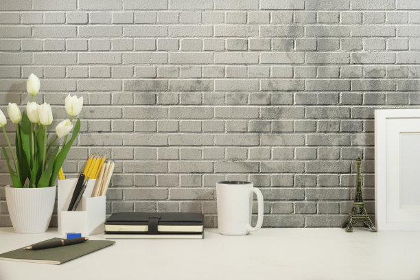 正面视图空白画框，室内植物，铅笔架，书和咖啡杯在白色的桌子上。最小的工作场所，复制你的文本空间。图片下载