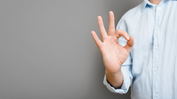 不可辨认的男子在衬衫显示Ok标志与手站在灰色背景，复制空间。手指手势象征认可、成功、酷。特写，横幅与空白的文本空间图片下载