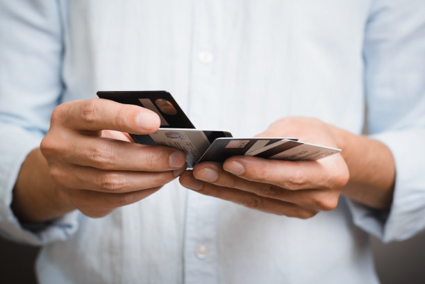 一名身穿蓝色衬衫的男子手持许多银行信用卡，站在室内，特写。商业和金融概念。选择性地关注借记卡图片下载