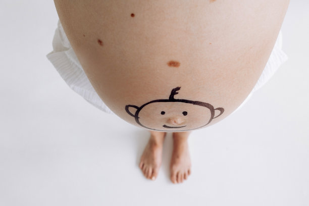 俯视图和特写视图孕妇的肚子与有趣的微笑娃娃脸绘制在它。图片下载