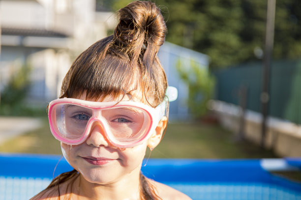 在自家泳池里戴泳镜的白人女孩。图片下载