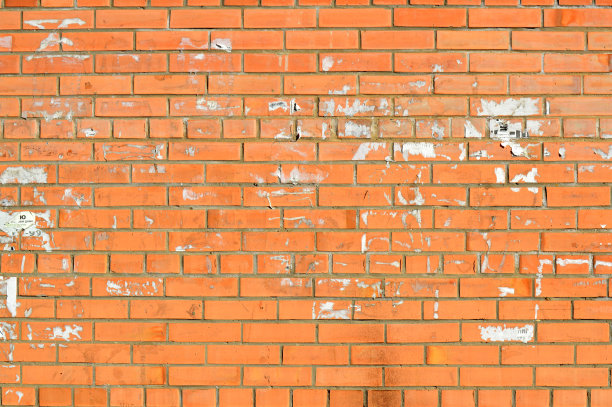 旧橘色砖墙。粉刷的仿旧墙面。古老的红色砖墙，上面有古老的广告标志。城市图片背景设计。灰泥损坏的建筑立面图片下载