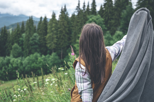 一个裹着毯子的年轻女子在山里。图片下载