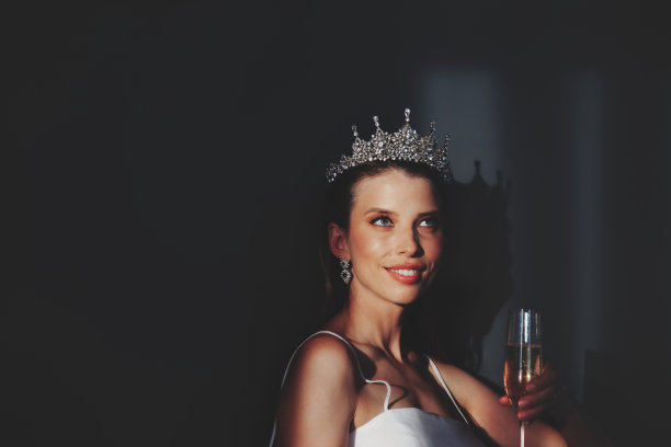 在黑暗的客厅里，以香槟为背景的时尚女性的肖像。化妆女性的家庭照片。女性美的概念、风格。复制文本空间图片下载