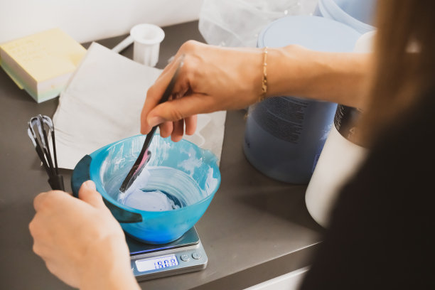 为染发准备染发剂的女人。在美容院染发。专业的巫师在沙龙里画头发。美容理念，护发图片下载