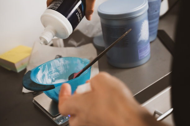 为染发准备染发剂的女人。在美容院染发。专业的巫师在沙龙里画头发。美容理念，护发图片下载