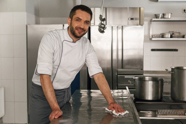 年轻英俊的男厨师在餐厅厨房清洁他的工作场所图片下载