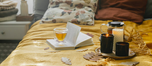 横幅形象设计。舒适的床上有一杯茶，蜡烛和一本打开的书。概念秋季舒适的家居室内，健康，周末放松图片下载