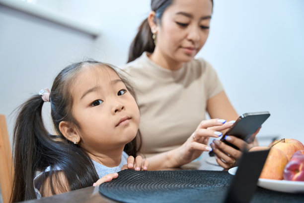 忙碌的女人和无聊的女孩坐在桌子旁摆弄小玩意图片下载