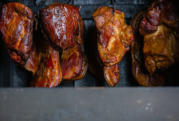 烟熏肉和腹部或山毛榉肉的近距离与黑色的外壳在熏制室或吸烟者，食物的概念图片下载