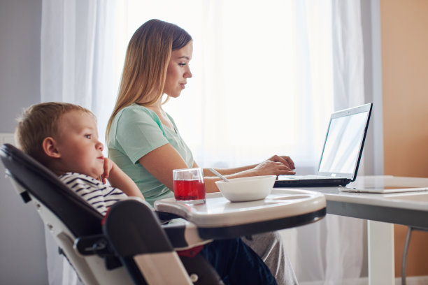 忙碌的母亲工作和喂养幼儿图片下载