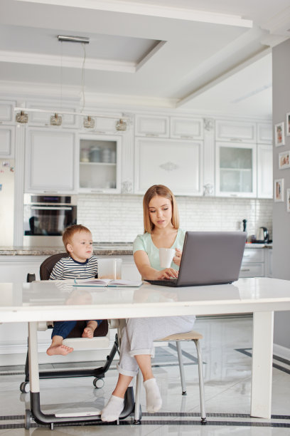 妈妈和儿子吃饭时使用笔记本电脑图片下载