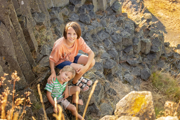孩子们在一个玄武岩柱的多边形结构上攀爬，这是捷克共和国Kamenicky Senov附近的自然遗迹Panska skala。图片下载