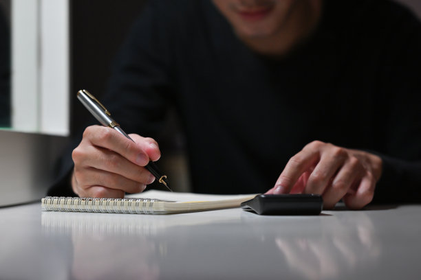 近距离的亚洲商人工作会计在晚上，而使用计算器的金融。商业和金融概念。图片下载