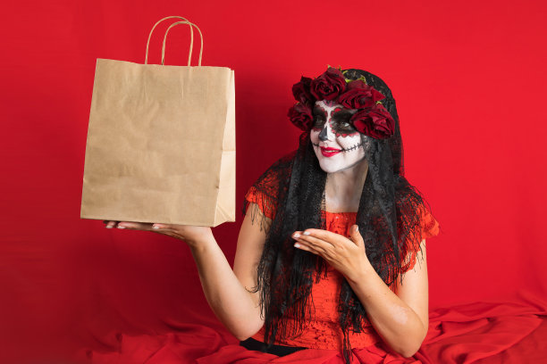 一名年轻女子穿着红色连衣裙和传统的糖头骨化妆的肖像，以庆祝Dia de los Muertos，即死亡之日图片下载