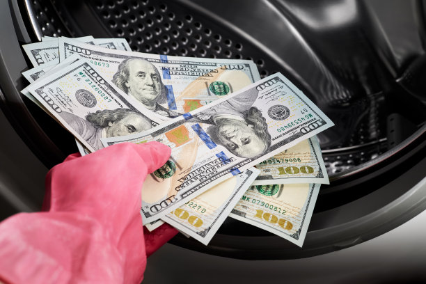 一个戴着橡胶手套的人把美元放进洗衣机的特写图片下载