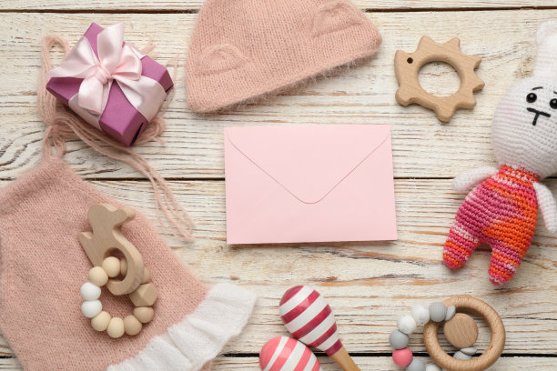宝宝派对聚会。信封四周是礼品盒和儿童用品，白色木制背景，平放图片下载