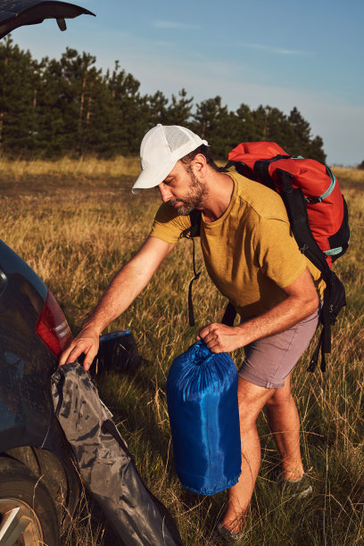 男人在大自然中露营，在户外拆行李和打包小帐篷，娱乐和爱好。图片下载
