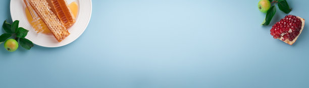 犹太新年。蜂蜜罐，蜂巢，苹果和石榴在简单的蓝色背景。犹太新年节日贺卡。犹太新年的节日属性。空间的文本。横幅。图片下载