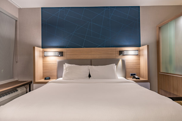 一个典型的美国酒店房间的室内夜景照片，有一张大号床。图片下载