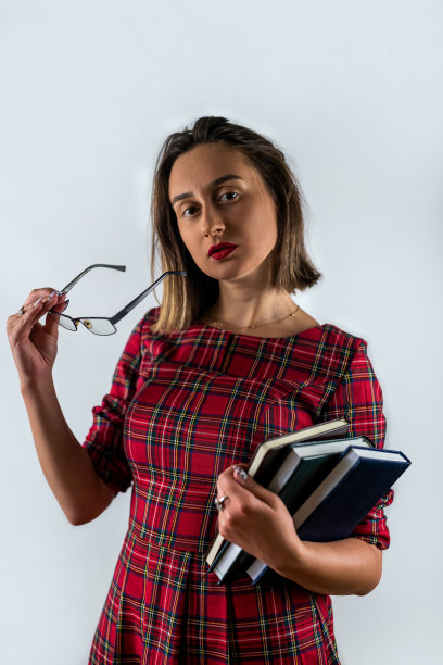 微笑美丽的年轻黑发女子穿着休闲白衬衫摆姿势拿着一本书。图片下载