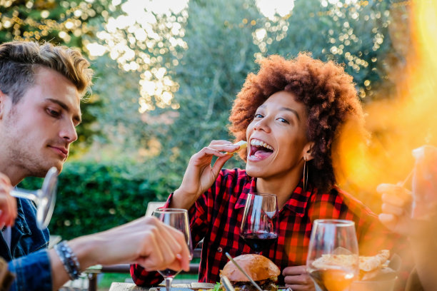 美丽的非洲裔美国女孩生活在健康的生活方式和微笑和开玩笑，而吃和喝红酒与她的朋友在户外酒吧餐厅图片下载