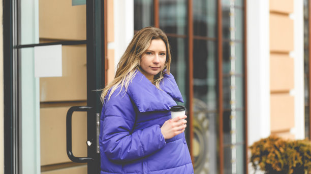 美女肖像时尚女子穿紫色夹克在街上。概念照片与一杯温暖的饮料图片下载