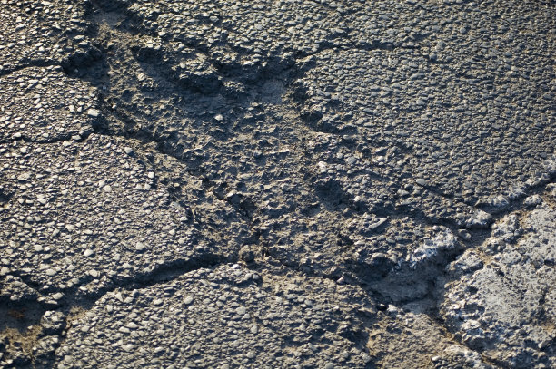 开裂的灰色沥青特写。图片下载