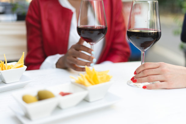 作物匿名的商业女性喝红葡萄酒，而花时间在一起工作后，在现代餐厅户外-两个商业女性在快乐的时间的细节图片下载