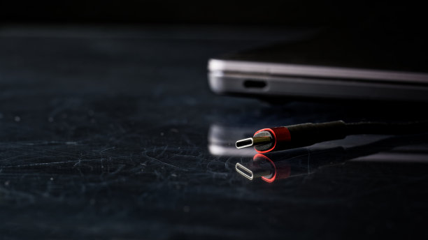 常用的黑色和红色usb -c型连接器旁边的轻薄笔记本或超极本。黑色划痕复古背景。连接和充电经常使用的流行小工具。有选择性的重点图片下载