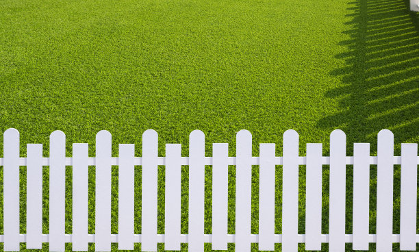 前院绿色人工草皮上白色木桩表面的光影图片下载