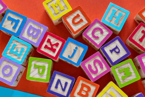 木制的彩色方块与字母在橙色的背景。学前教育，阅读，字母表。回归学校理念图片下载