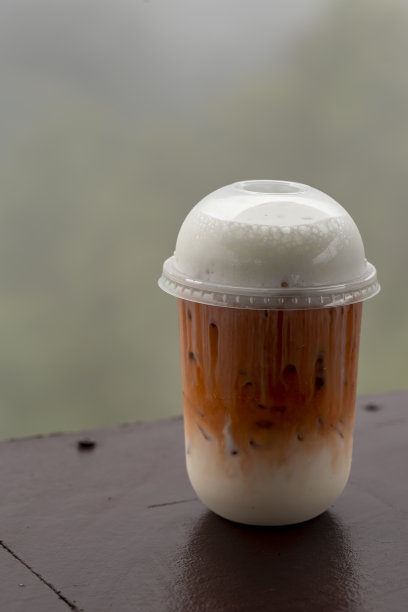 塑料玻璃冰奶茶的特写照片和模糊的背景。图片下载