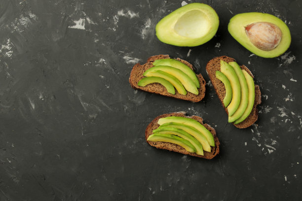 黑色混凝土背景上是面包和牛油果片的三明治。制作三明治。俯视图图片下载